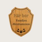 Här bor-skylt i trä med formen av en sköld