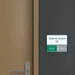 Rumsskylt med ledigt/upptaget funktion vid brun dörr