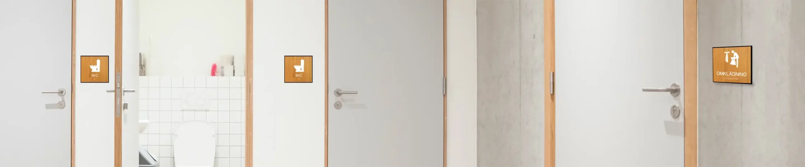 Taktila skyltar i trä till omklädningsrum och WC