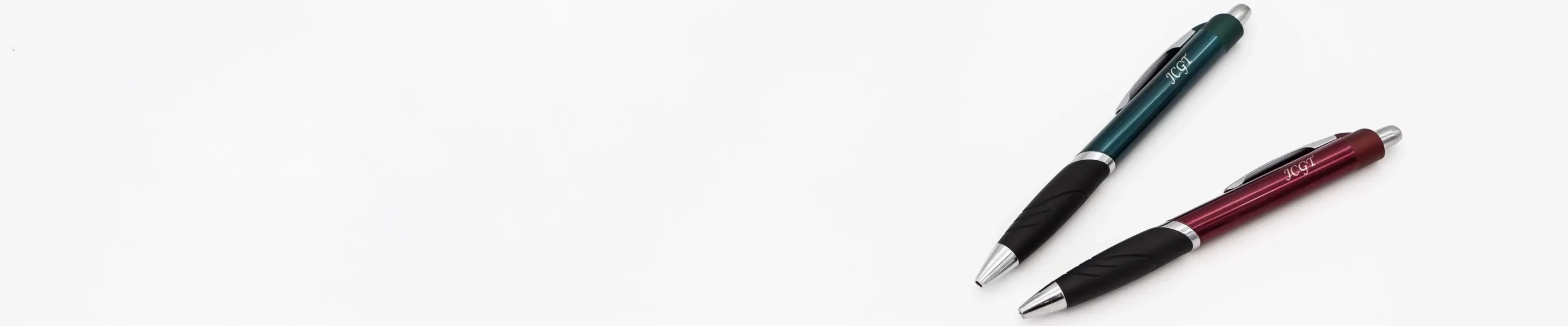 En grön och en röd penna med graverad text - jcgt.se