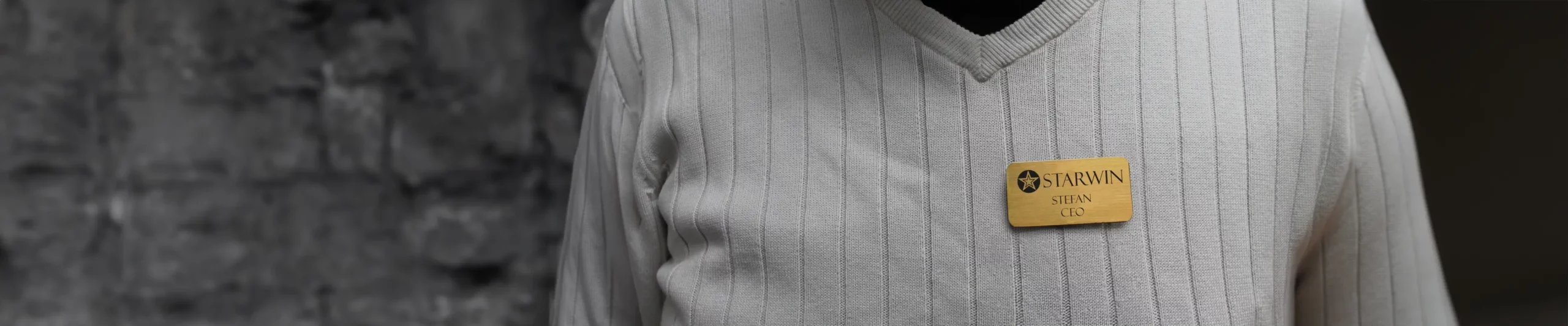 En man med en graverad namnskylt i mässing med namn och titel på