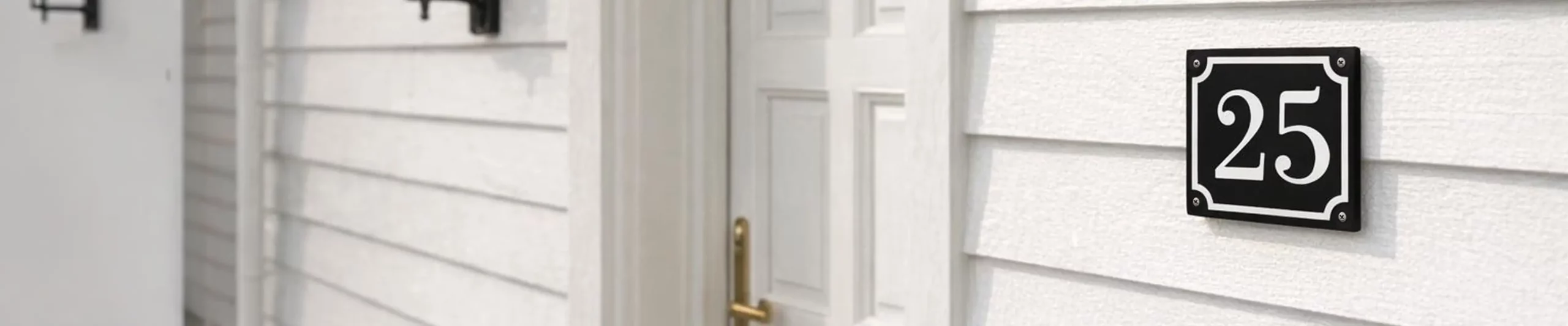 Svart husnummerskylt på en vit husvägg