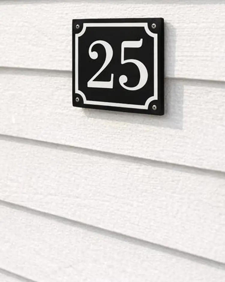 Husnummerskylt 25 i svart aluminium på vit husvägg